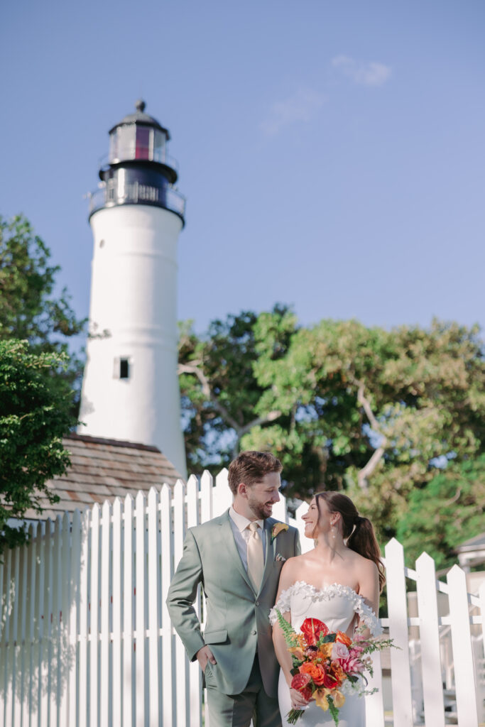 Couple sharing a tender moment, gazing at each other by the lighthouse during their dream wedding at the Hemingway House Museum, creating a serene and intimate atmosphere.