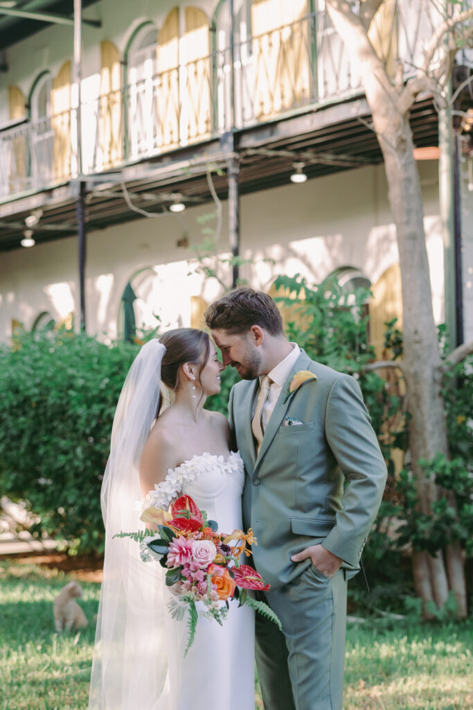 Couple sharing a tender moment, gazing at each other by the lighthouse during their dream wedding at the Hemingway House Museum, creating a serene and intimate atmosphere.