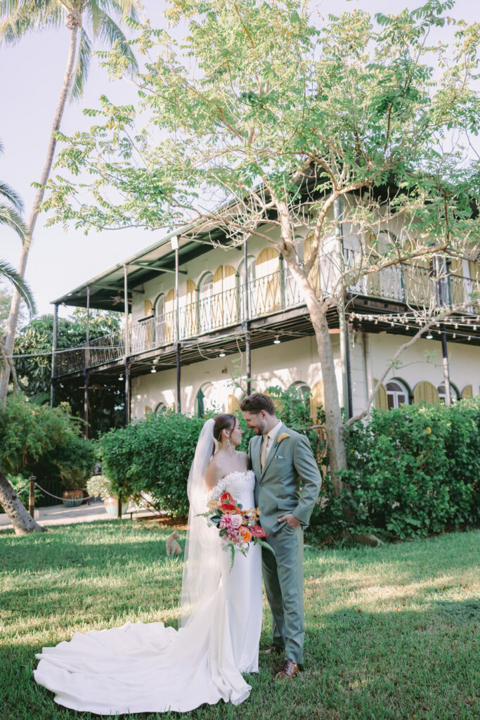 Couple sharing a tender moment, gazing at each other by the lighthouse during their dream wedding at the Hemingway House Museum, creating a serene and intimate atmosphere.