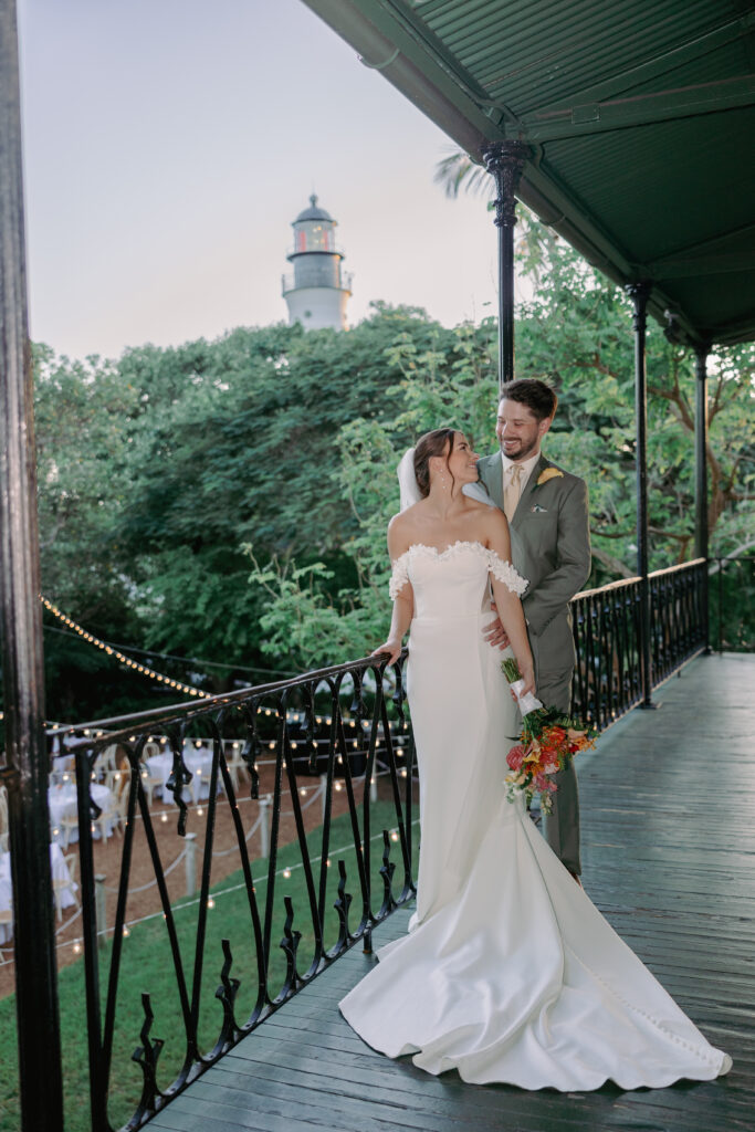 Couple looking at each other with the lighthouse in the background during their dream wedding at the Hemingway House Museum, capturing a moment of pure connection.