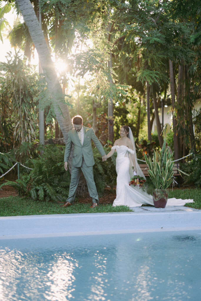 Couple walking hand in hand by the pool at their dream wedding at the Hemingway House Museum, capturing a moment of pure connection.
