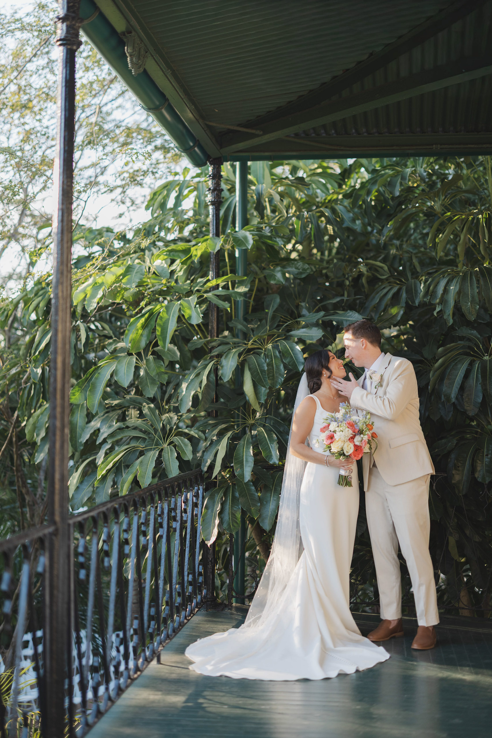 Bride and groom share a quiet moment on the balcony of the Hemingway House surrounded by lush green gardens.