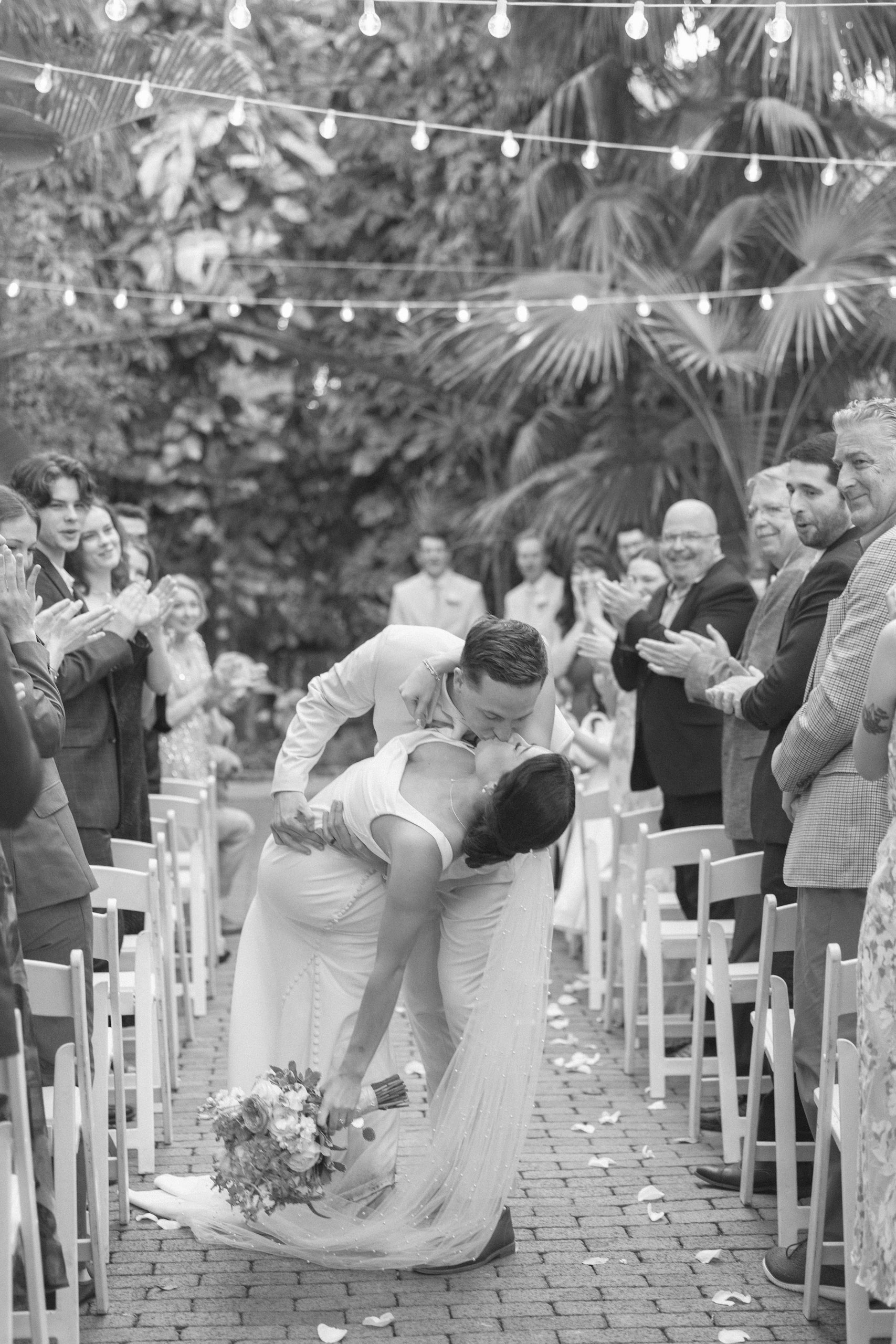 Black and white photo of bride and groom kissing in the aisle of their garden ceremony at the Hemingway House