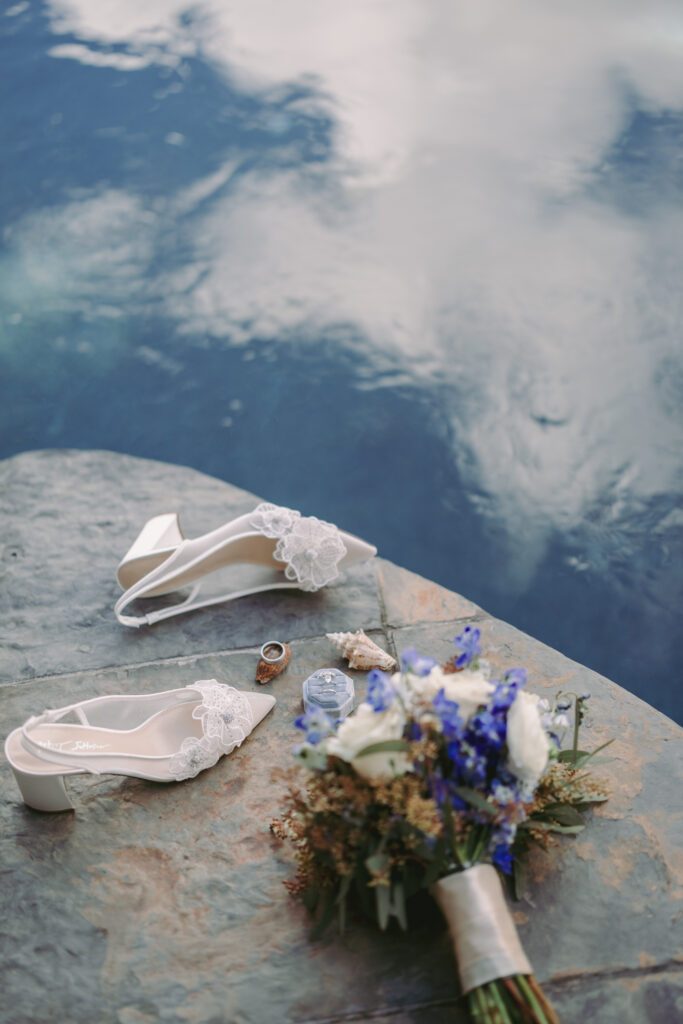White bridal high heels with a blue and white floral bouquet.