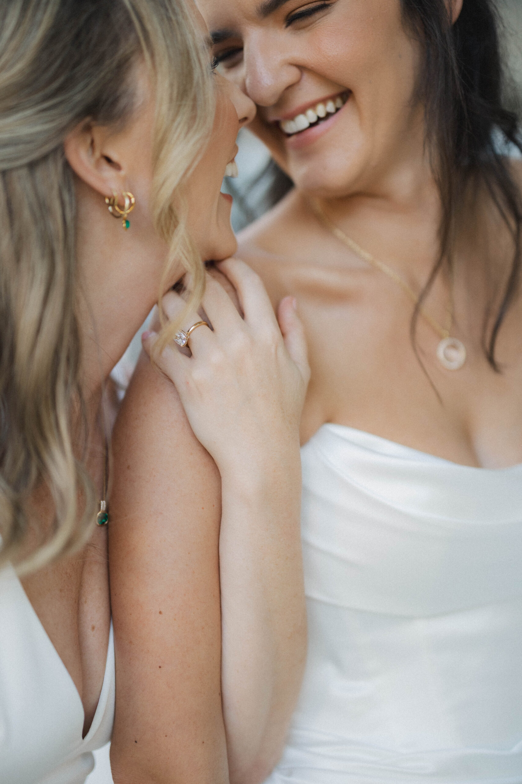 Two brides smile at each other during the wedding portraits.