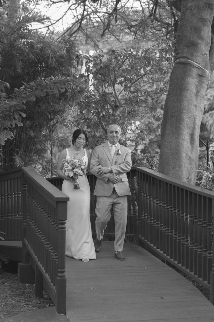 black and white photo of father walking his daughter to the ceremony site.