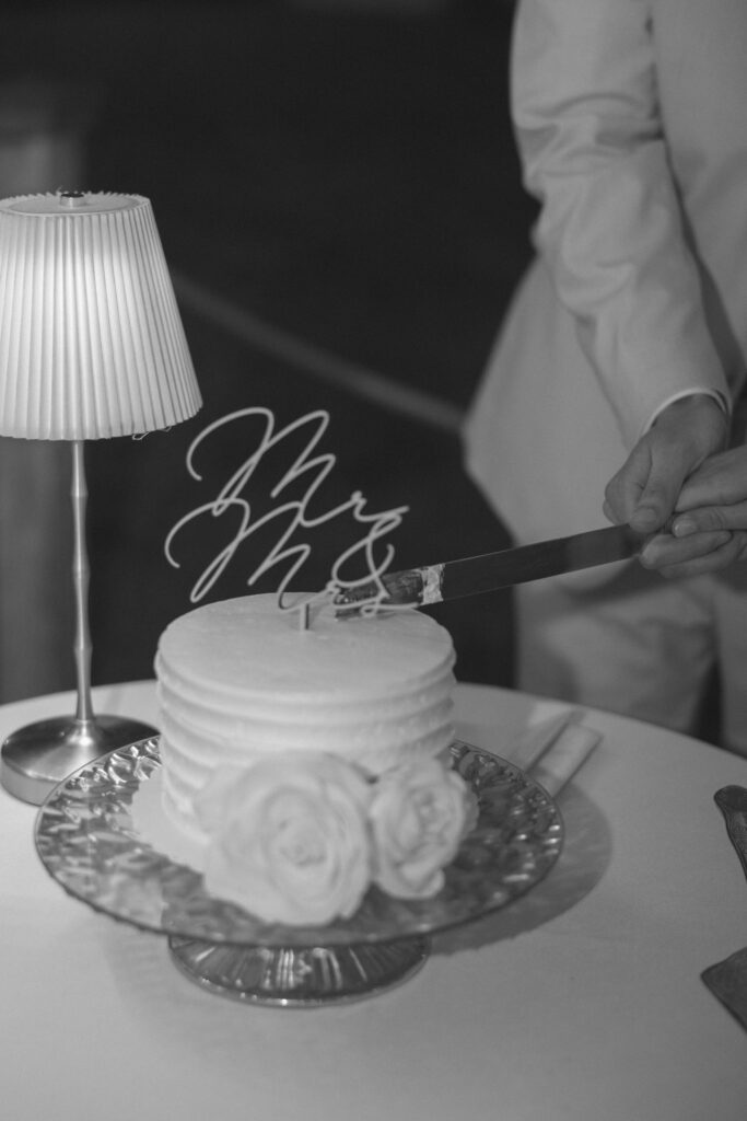 Black and white photo of the couple cutting their wedding cake
