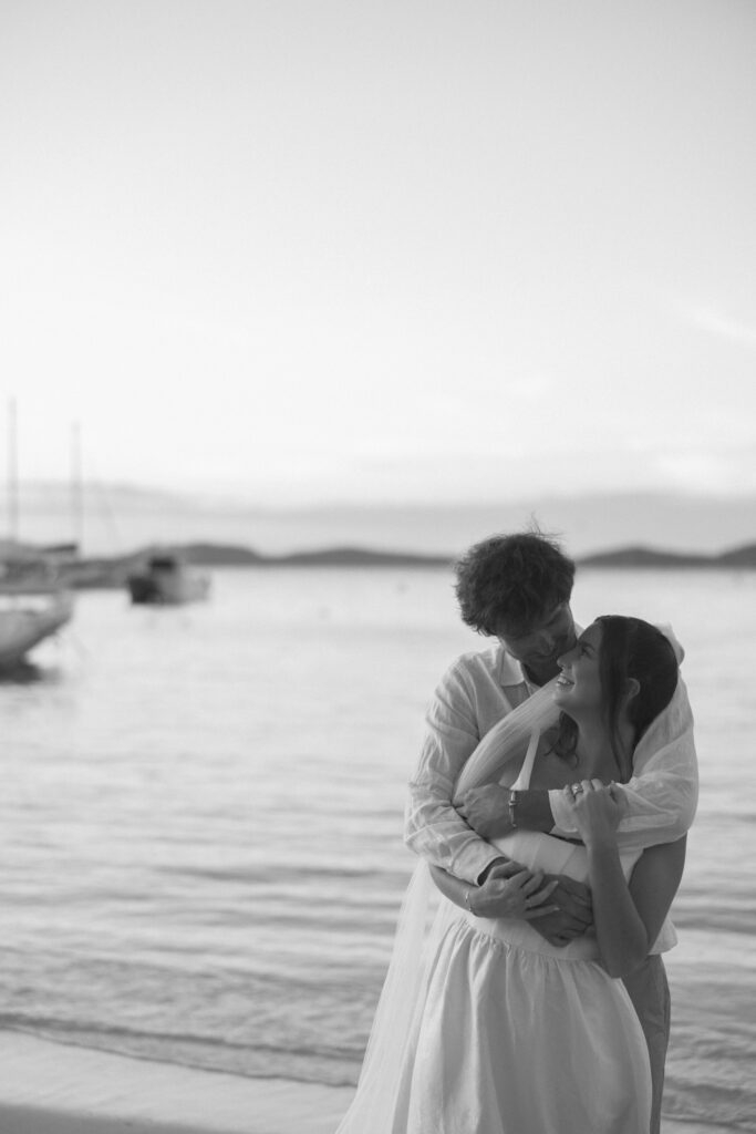Black and white images of bride and groom embracing on the beach