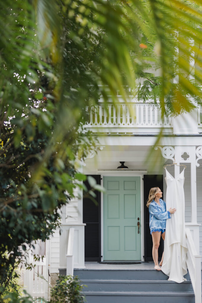 A bride looking at her dress as it's hanging on the porch of a historic Conch house in Key West