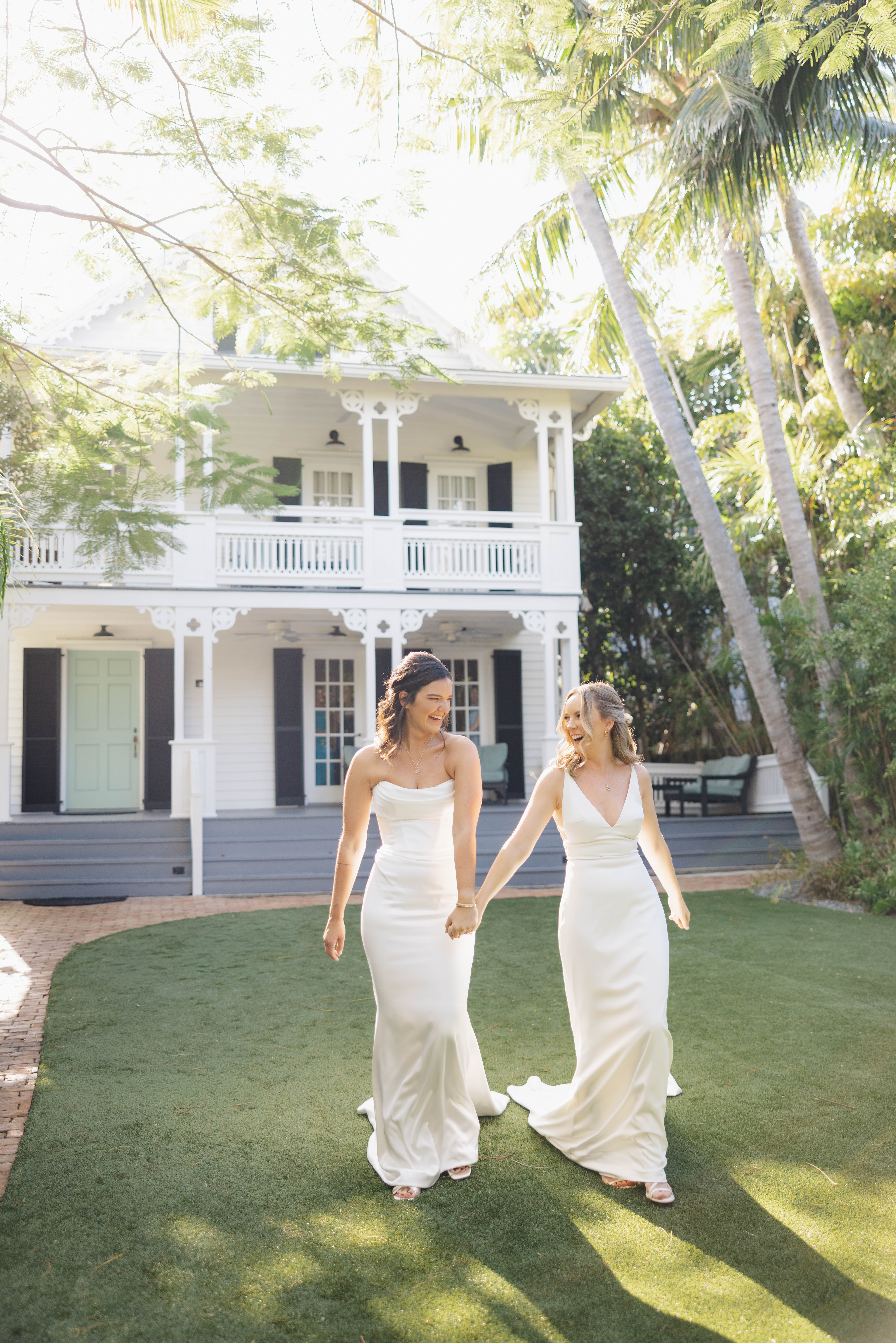 Two brides holding hands in from of a historic Key West Conch House before their wedding