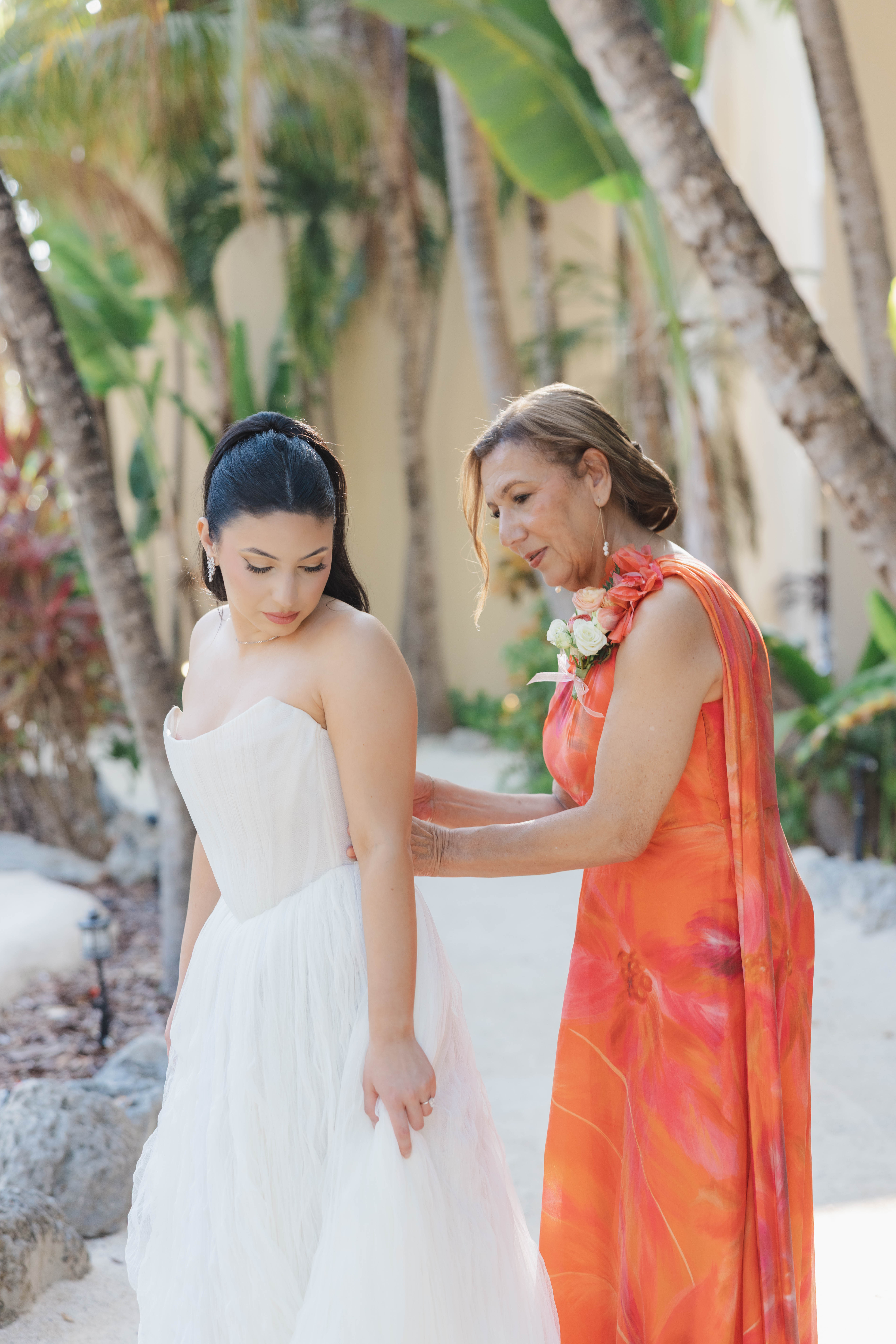 Mother of the bride helping the bride zip her dress
