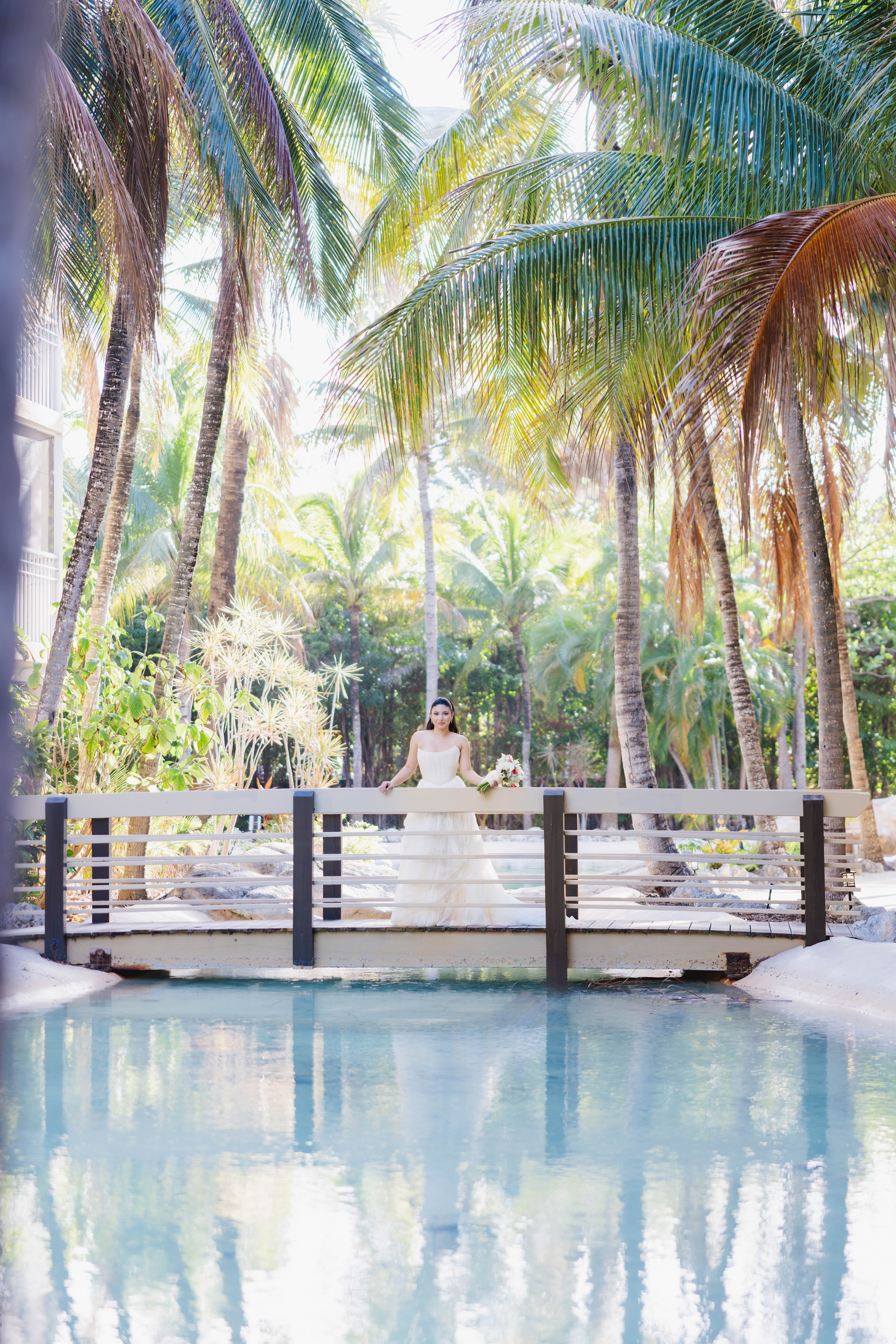 Bride standing on a bridge surrounded by palm trees