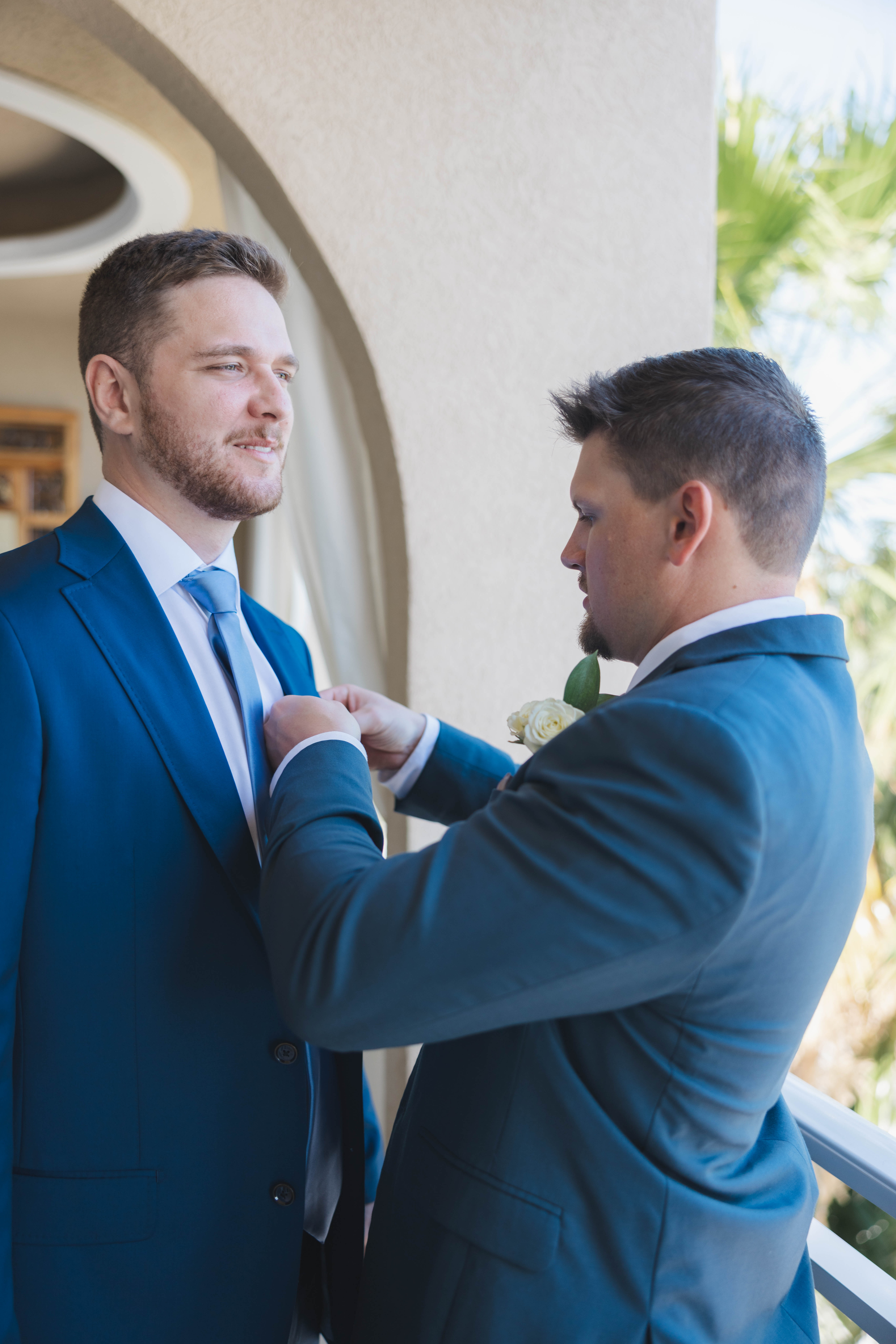 Groomsmen helping groom with his suit