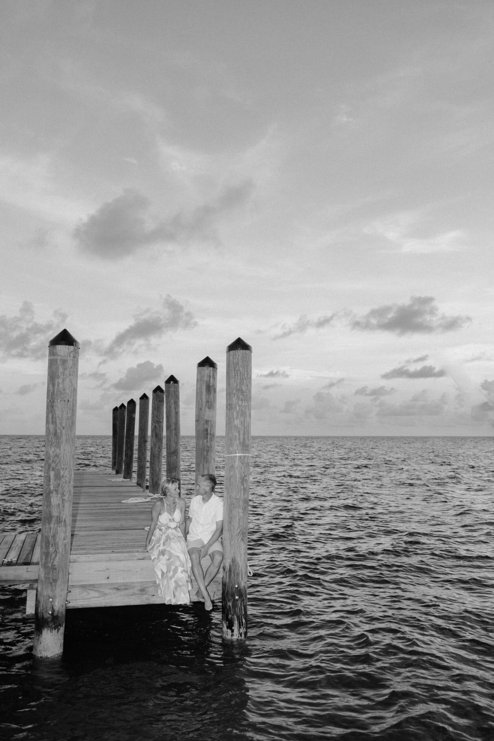 A black and white image of a couple sitting on a pier at a Key West resort