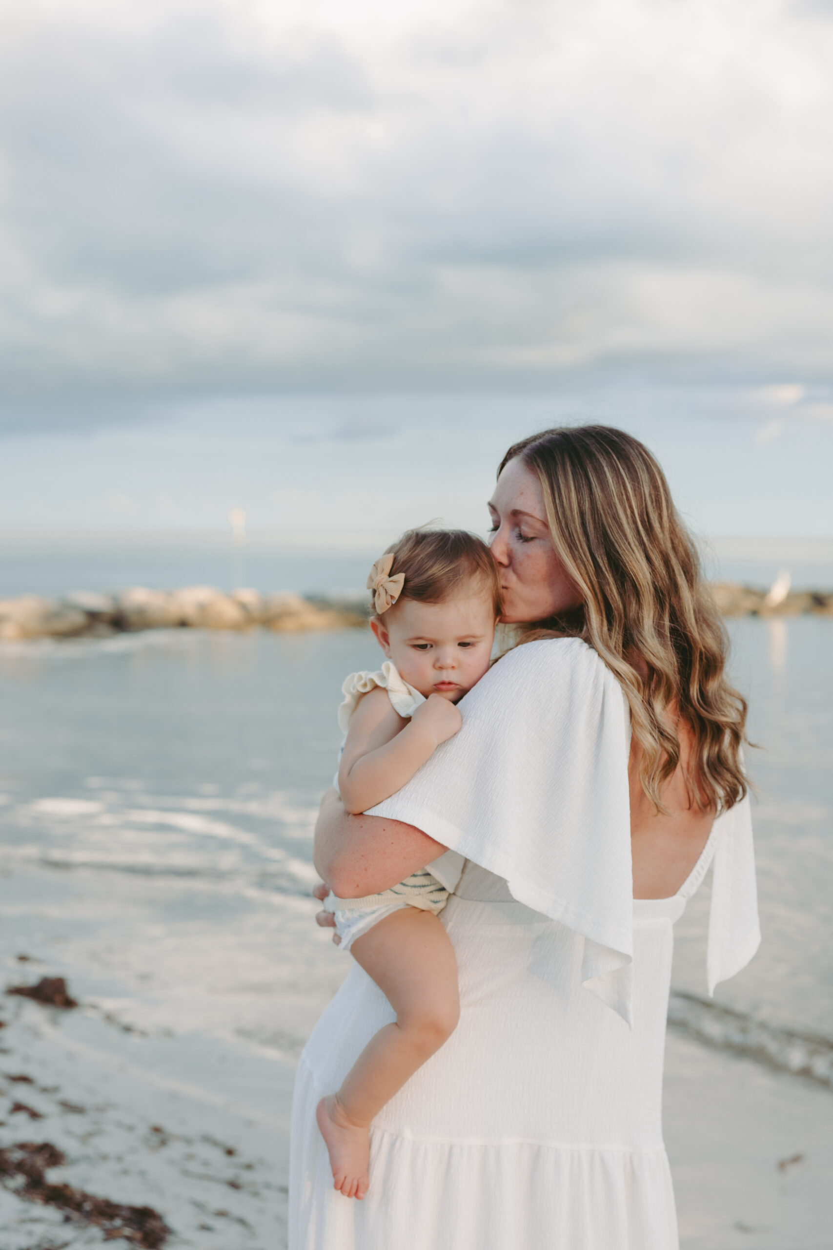 A mother kissing her daughter's head at a Key West beach