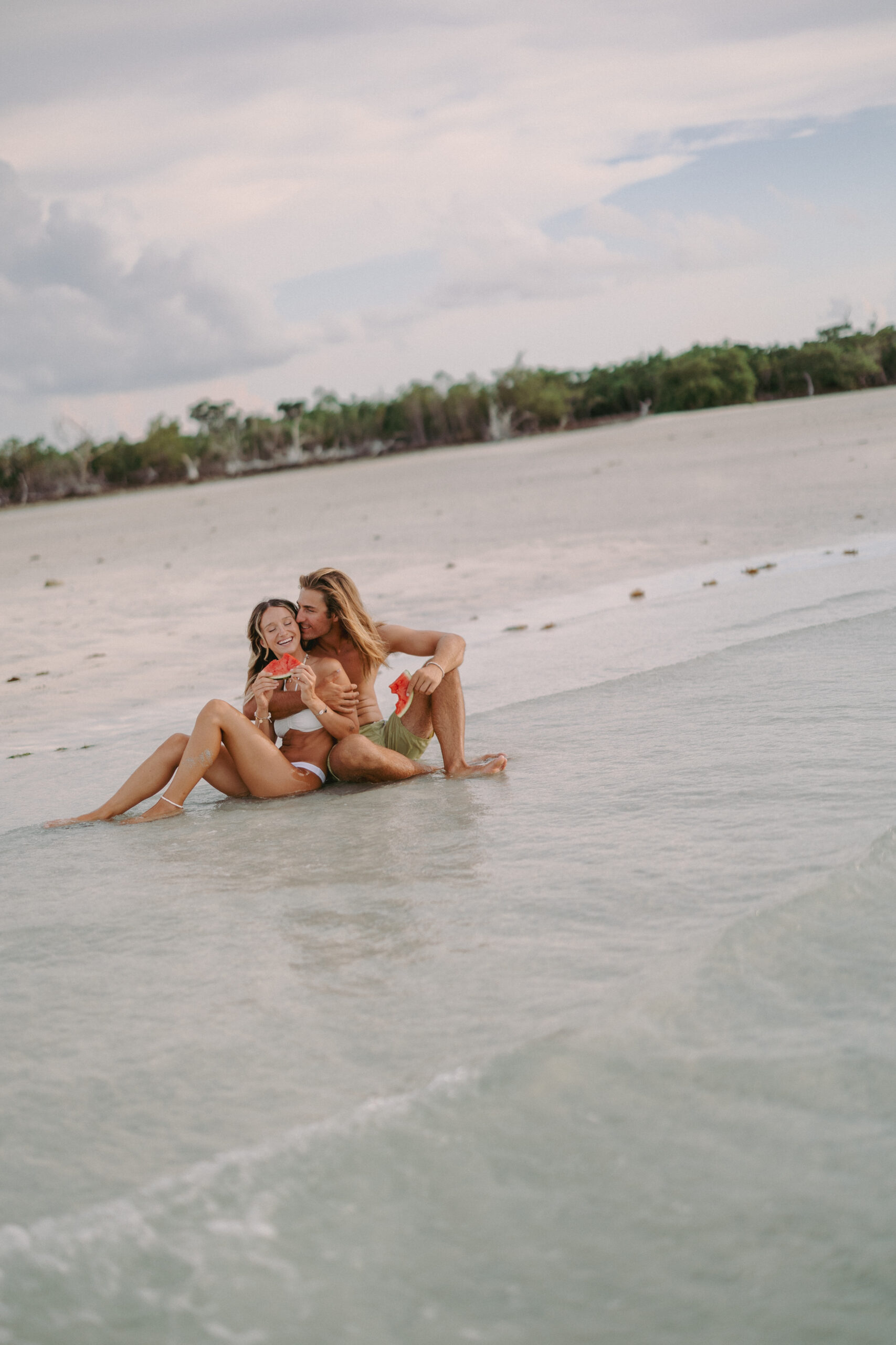 Couple snacking on watermelon at a private sandbar during a Key West sunset sandbar session