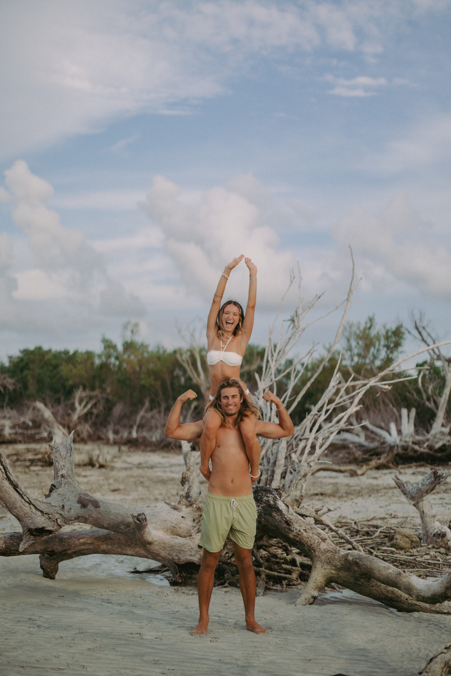 Couple posing on a beach sandbar in front of a large branch