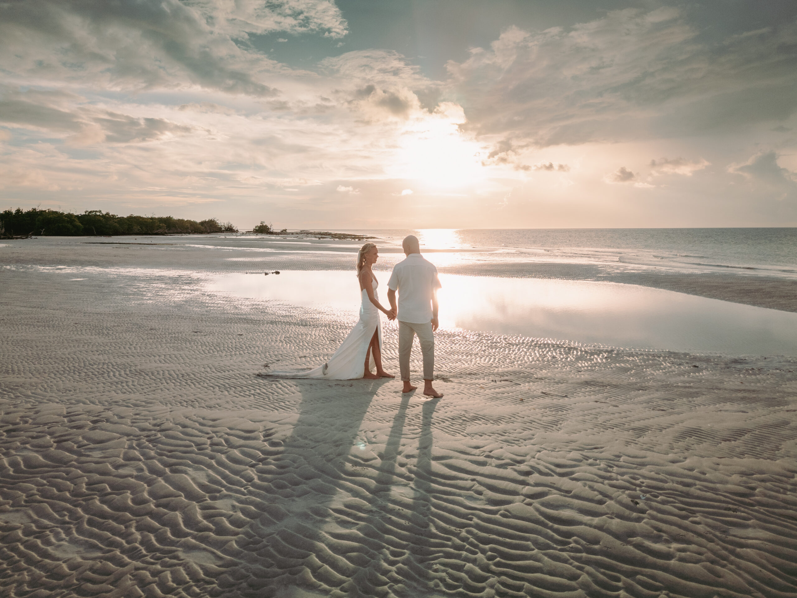 Couple holding hands on the beach at sunset
